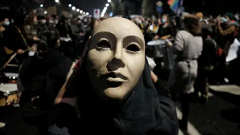 Reuters A demonstrator wearing a mask takes part in protest against imposing further restrictions on abortion law, near the house of Law and Justice leader Jaroslaw Kaczynski in Warsaw, Poland, 23 October, 2020.