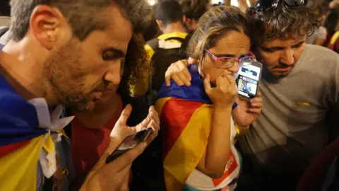 Getty Images Independence supporters listen to Carles Puigdemont's speech on phones in Barcelona, 21 October