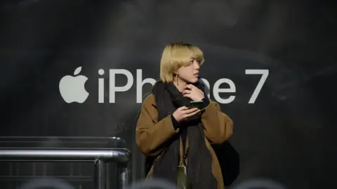 Getty Images Chinese woman with phone in front of iPhone logo