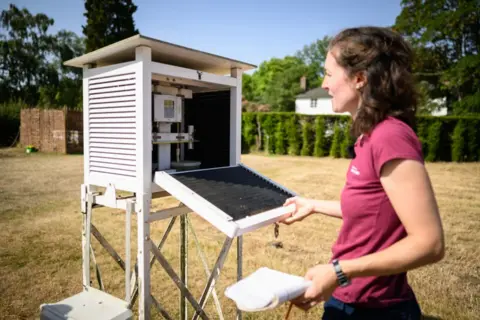 Leon Neal / Getty Images Assistant horticulturist Katie Martyr at a weather station