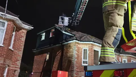 Firefighter operating turntable ladder to reach robbery suspect on roof