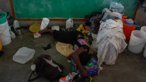 Getty Images A woman sleeps on the floor of a classroom in a school that has become a shelter for displaced people