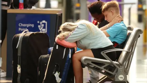 Reuters A woman rests her head on her luggage at Manchester Piccadilly Station during the rail strike