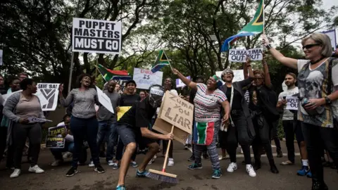 Getty Images A protest outside the Gupta family compound in Johannesburg earlier this year