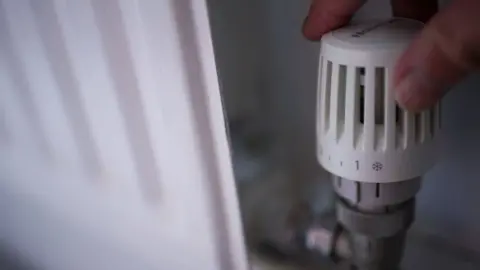 PA Hand turning down a radiator thermostat