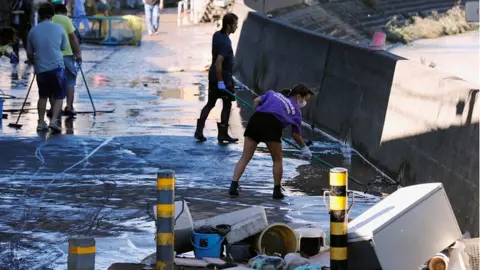 Reuters People clean up debris after floodwaters caused by Typhoon Hagibis receded in a residential area, in Kawasaki, Japan, October 13, 2019