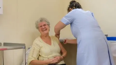 IOM GOV Ann Corlett receiving the vaccine