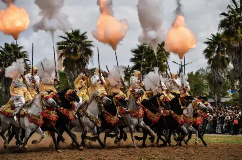 Getty Images Men charge on horseback while firing muskets.