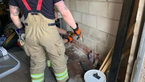 Nottinghamshire Fire and Rescue Service Fire crew chiselling through wall