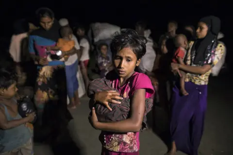 Paula Bronstein/ Getty Images Rohingya Muslims fleeing violence in Myanmar hold children and belongings.