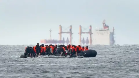 PA Media A small boat carrying migrants across the Channel