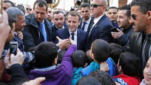 AFP French President Emmanuel Macron is surrounded by security as he greets children in the streets of Algiers, Algeria- Wednesday 6 December 2017