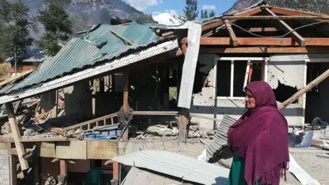 Getty Images A resident stands in front of her damage house a day after cross border shelling in Jora, a village of Neelum valley in Pakistan-administered Kashmir on October 20, 2019. - At least nine people were killed on October 20 in firing along the de facto India-Pakistan border in Kashmir