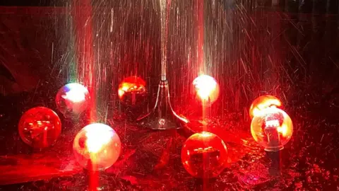 BBC Fountain surrounded by glass balls lit up in orange and red