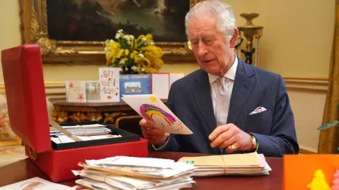 PA Media King Charles holding a get-well cards