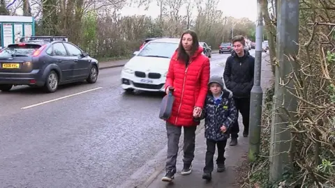 BBC Alice Macintosh on a pavement walking kids to school