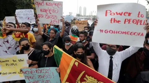 EPA Protesters hold up signs calling for President Rajapaksa to resign outside parliament in Colombo