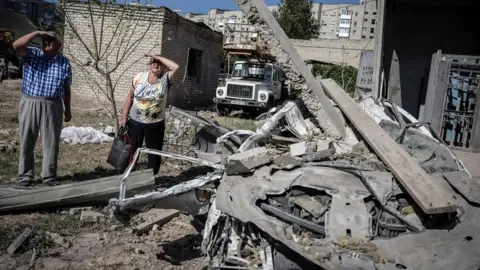 Reuters Local residents stand outside an apartment building damaged by a Russian missile strike, amid Russia's attack on Ukraine, in Pokrovsk, Donetsk region, Ukraine August 8, 2023.