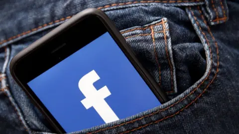 Getty Images Phone with Facebook logo in pocket