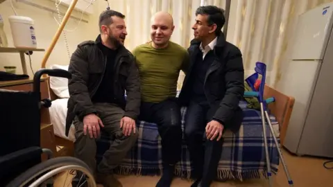 Reuters Rishi Sunak and Volodymyr Zelensky meet a wounded war veteran during a visit to a hospital in Kyiv