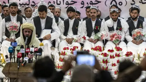 Getty Images Afghan grooms look on during a mass wedding ceremony at a wedding hall in Kabul