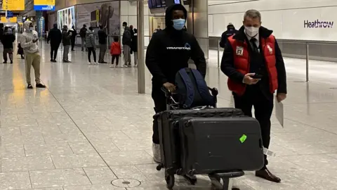 PA Media A man walks through arrivals at Heathrow