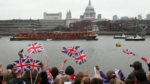 PA Media Onlookers cheer on the Queen's barge on the Thames