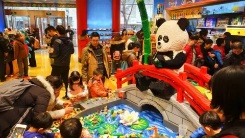 Getty Images Shoppers look at a giant panda shaped decoration at the Lego flagship store at Wangfujing Street on February 23, 2019 in Beijing, China. Lego Group, the world's leading toy maker, unveiled its first flagship store in Beijing on Friday