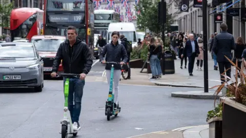 Getty Images Man and woman riding e-scooter in central London