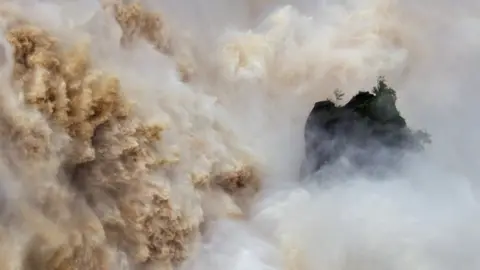 NEIL PRITCHARD Huge volumes of water crash down the Barron Falls in Kuranda, Queensland