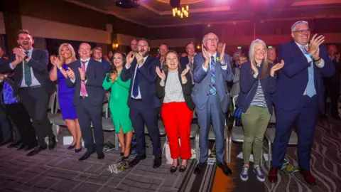 Liam McBurney/PA Media DUP representatives applaud Sir Jeffrey Donaldson