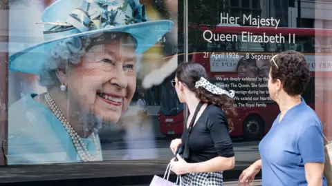 Getty Images People look at a portrait of Queen Elizabeth II in the window of a shop on Oxford Street in London on 12 September 2022