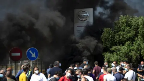 Andalou Agency via Getty Images Protestors burned tyres in front of Nissan's plant in Barcelona which is being closed down