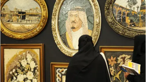 AFP A Saudi woman looks at a portrait of the Saudi King during an interior design fair in the Red Sea city of Jeddah, 8 November 2017