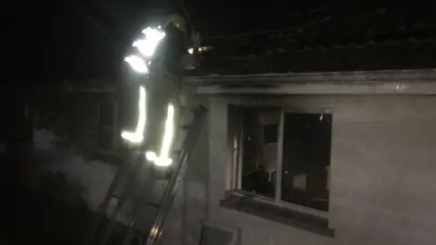 Jersey Fire and Rescue Firefighters on a roof in the dark