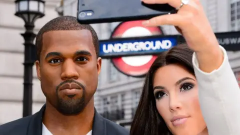 Madame Tussauds Kanye West's wax figurine alongside Kim Kardashian's during a museum promotion outside a London tube station