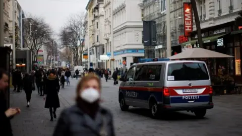 Reuters A police car is seen as pedestrians walk along a shopping street after the Austrian government placed roughly two million people who are not fully vaccinated against the coronavirus disease (COVID-19) in lockdown