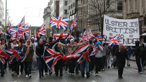 Getty Images/AFP A vote to reduce flag-flying at Belfast City Hall led to protest marches and rallies in 2012