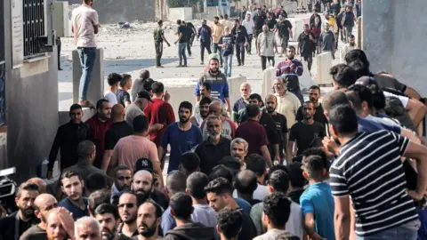 Getty Images A crowd of Palestinian workers cross through the Kerem Shalom crossing