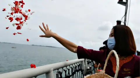 Reuters Woman throwing flowers into the sea