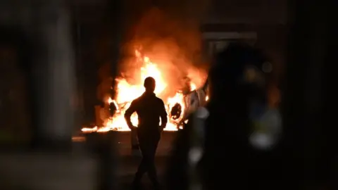 Getty Images An upturned car burns at the scene of disorder in Cardiff