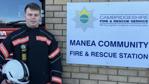 Seb Noble/BBC Firefighter next to sign