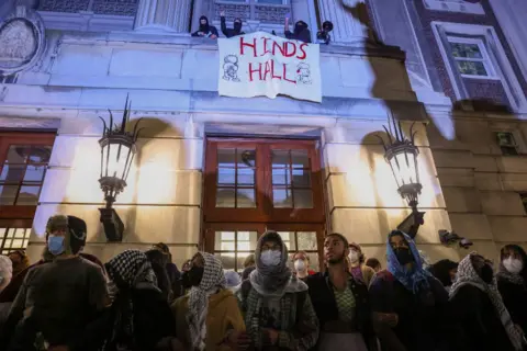 Reuters Protesters stand in front of Columbia's Hamilton Hall, which has a sign draped over it reading "Hinds Hall"