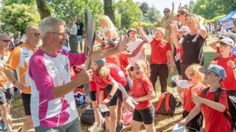 Getty Images Roger Graves holding the baton to cheering children