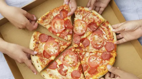 Children grabbing pizza from a box.