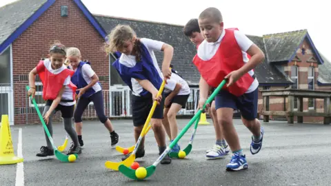 Getty Images School children play hockey outdoors