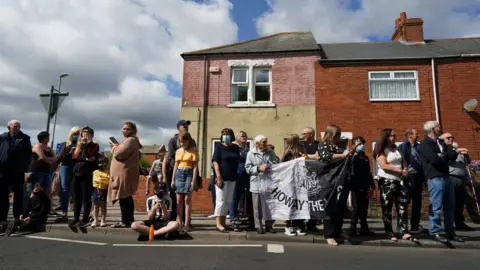 Getty Images Well-wishers line the street in Ashington with some holding a Newcastle United flag