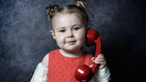 A young girl holds a phone