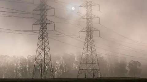 Getty Images Power pylons shrouded in smoke with the sun behing