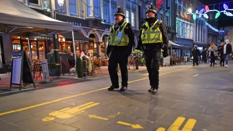 PA Media Two South Wales Police officers in uniform and helmets patrol bars area in Cardiff city centre after firebreak lockdown ends and venues reopened in November